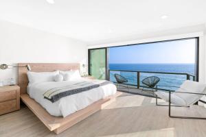 a bedroom with a bed and a balcony with the ocean at Aquazzura - By Stay Awhile Villas in Malibu