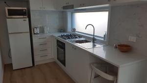 a kitchen with a sink and a stove and a window at Kooyong in Northmead