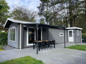 a shed with a table and chairs on a patio at Chalet vakantiepark Beekbergen in Beekbergen