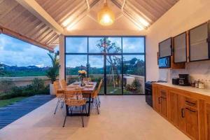 eine Küche mit einem Tisch und Stühlen sowie einem großen Fenster in der Unterkunft New 3BR villa,Sunset &ricefield views Canggu area! in Kerobokan