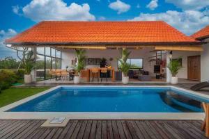 einen Pool in einem Haus mit orangefarbenem Dach in der Unterkunft New 3BR villa,Sunset &ricefield views Canggu area! in Kerobokan