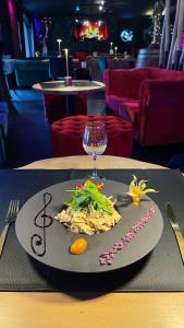 een bord eten en een glas wijn op een tafel bij La Terrasse Des Spas in Hazebrouck