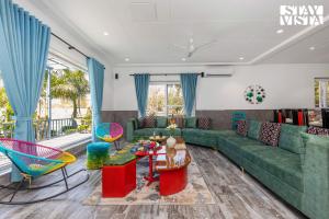 a living room with a green couch and colorful furniture at Corbett Calling with Projector Set-Up by StayVista in Rāmnagar +30 photos