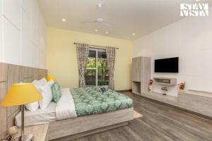 1 dormitorio con 1 cama y TV en Corbett Calling with Projector Set-Up by StayVista en Rāmnagar
