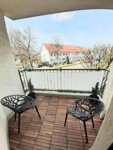 a balcony with two chairs and a view of a house at Helle freundliche Wohnung am Stadtpark in Bobingen