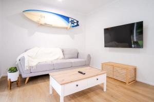 a living room with a couch and a surfboard on the wall at Pet Friendly Battery Hill Home away from Home in Caloundra