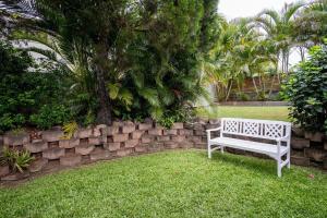 a white bench sitting in the grass next to a stone wall at Pet Friendly Battery Hill Home away from Home in Caloundra