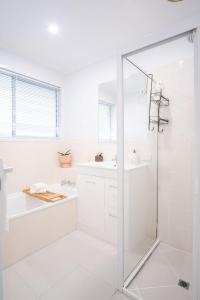 baño blanco con ducha y lavamanos en Pet Friendly Battery Hill Home away from Home en Caloundra