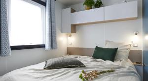 a bedroom with a bed with white sheets and a window at Camping Porte des Vosges in Bulgnéville +65 photos