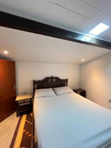 um quarto com uma grande cama branca num quarto em Apartamento no Centro em Porto Seguro