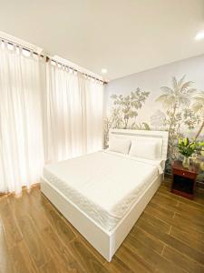 a bedroom with a white bed with white curtains at AuLe Dorm Room in Ho Chi Minh City