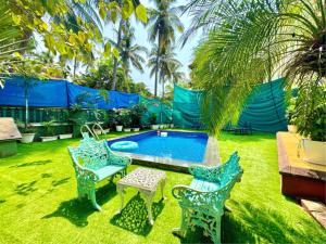 een achtertuin met een zwembad en twee stoelen en een tafel bij Rustic Private Pool Villa # 8 by SAZJ Hospitality in Saligao