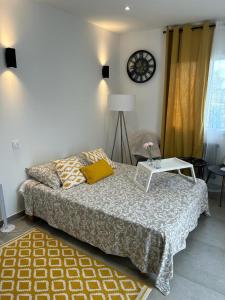 ein Schlafzimmer mit einem Bett mit einem Tisch und einer Uhr in der Unterkunft Chambre près de Walygator et Aqualand in Brax