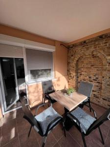 a dining room with a table and chairs and a brick wall at Guest House LILA in Sombor