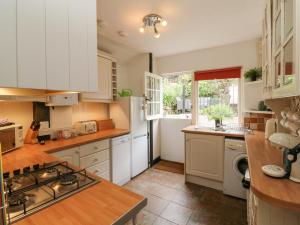 cocina con armarios blancos y fogones en Harbour Cottage, en Ilfracombe