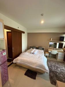 een slaapkamer met een groot bed en een bureau bij Apartemen Grand Kamala Lagoon by Abel Stay Luxury in Pekayon Satu