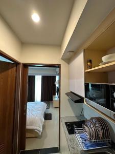 a room with a bed and a kitchen with a stove at Apartemen Grand Kamala Lagoon by Abel Stay Luxury in Pekayon Satu