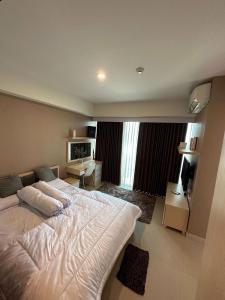 een slaapkamer met een groot bed en een televisie bij Apartemen Grand Kamala Lagoon by Abel Stay Luxury in Pekayon Satu