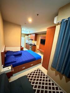 een slaapkamer met een blauw bed en een keuken bij Apartemen Grand Kamala Lagoon by Abel Stay Luxury in Pekayon Satu