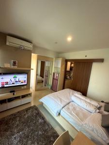 a bedroom with a bed and a flat screen tv at Apartemen Grand Kamala Lagoon by Abel Stay Luxury in Pekayon Satu