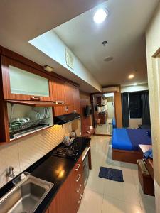 een keuken met een wastafel en een bed in een kamer bij Apartemen Grand Kamala Lagoon by Abel Stay Luxury in Pekayon Satu