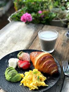 a plate of breakfast food with eggs and fruit and a glass of milk at La Maison du Laoshay Lijiang in Lijiang