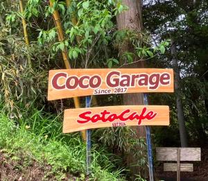 una señal para un garaje de coogee delante de un árbol en Guesthouse Coco Garage, en Kirishima