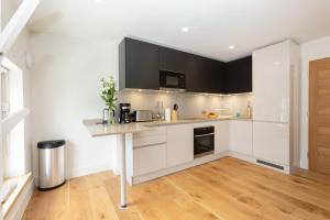 a kitchen with white cabinets and a wooden floor at Central Fitzrovia - 1BR - CityApartmentStay in London