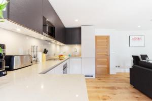 a kitchen with white counter tops and a black couch at Central Fitzrovia - 1BR - CityApartmentStay in London