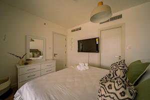 a bedroom with a bed with a dresser and a television at Raha Lofts Hosted By Voyage in Abu Dhabi