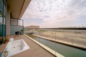 Raha Lofts Hosted By Voyage في أبوظبي: حوض استحمام على شرفة المبنى