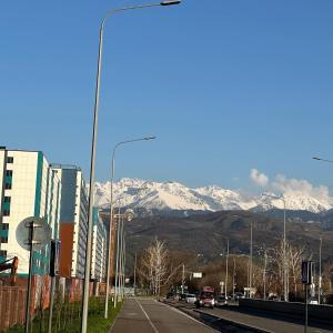 a city street with snow covered mountains in the background at ЖК Ashyq Tobe in Almaty