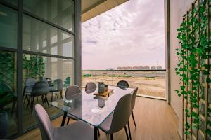 une salle à manger avec une table, des chaises et une grande fenêtre dans l'établissement Raha Lofts Hosted By Voyage, à Abu Dhabi