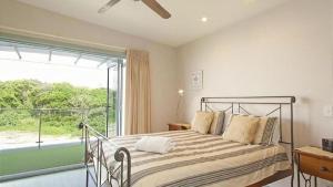 a bedroom with a bed and a large window at Nosie 2 in Sawtell