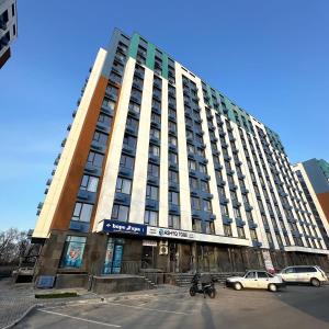 a tall building with cars parked in front of it at ЖК Ashyq Tobe in Almaty