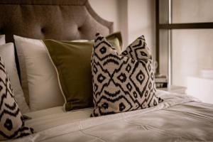 un letto con cuscini bianchi e cuscini verdi di Raha Lofts Hosted By Voyage a Abu Dhabi