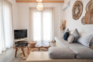 a living room with a couch and a tv at Epithea Suites Kythnos 4 με ιδιωτική πισίνα in Kithnos