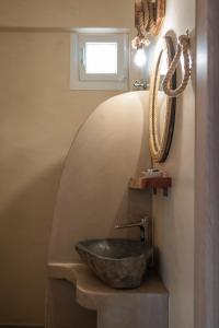 a bathroom with a stone sink and a mirror at Epithea Suites Kythnos 4 με ιδιωτική πισίνα in Kithnos +23 photos