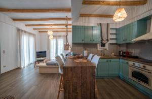 a kitchen with blue cabinets and a table with white chairs at Epithea Suites Kythnos 4 με ιδιωτική πισίνα in Kithnos