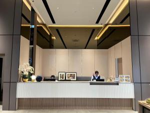 a man standing at a reception desk in a hotel lobby at Hatyai Midtown Hotel in Hat Yai