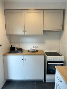 een keuken met witte kasten, een wastafel en een fornuis bij AMAROOM apartments 2 in Karlsruhe