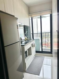 a small kitchen with a refrigerator and a window at Private 1 Bedroom at Niche Mono Mega Space Bangna in Bangna