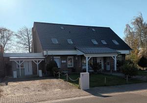 ceglany dom z czarnym dachem w obiekcie Haus Rosi w mieście Friedrichskoog-Spitz