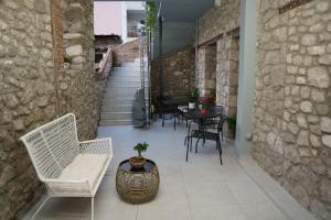 un patio con sillas, una mesa y una pared de piedra en MONOPATI HOUSE, en Mouzákion