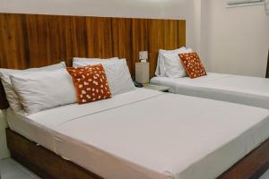 two beds in a hotel room with white and orange pillows at Tsai Hotel and Residences in Cebu City