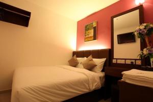1 dormitorio con cama blanca y espejo en AVARIA SIGNATURE en Melaka