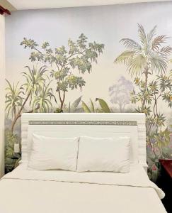 a bedroom with a white bed with a mural of palm trees at AuLe Dorm Room in Ho Chi Minh City