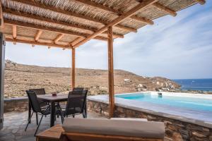 a patio with a table and chairs and a swimming pool at Epithea Suites Kythnos 5 με ιδιωτική πισίνα in Kithnos