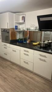 cocina con armarios blancos y encimera negra en Hotel KRONE habitación individual en Zäziwil