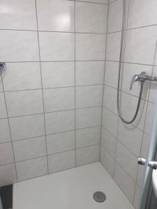 La salle de bains est pourvue d'une douche et d'un mur en carrelage blanc. dans l'établissement Hotel KRONE habitación individual, à Zäziwil